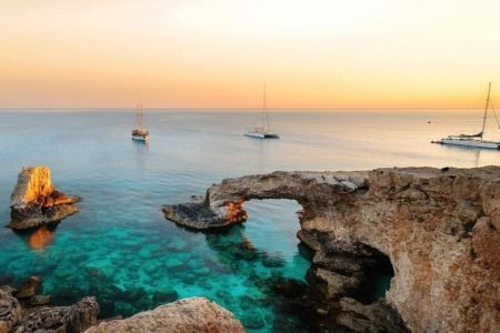Scenic view of Love Bridge in Ayia Napa, Cyprus, featuring natural rock formations over turquoise Mediterranean waters.