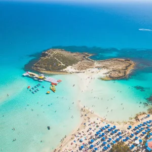 cenic view of Nissi Beach in Ayia Napa, Cyprus, with turquoise waters, soft white sand, and sunbathers relaxing under clear blue skies.